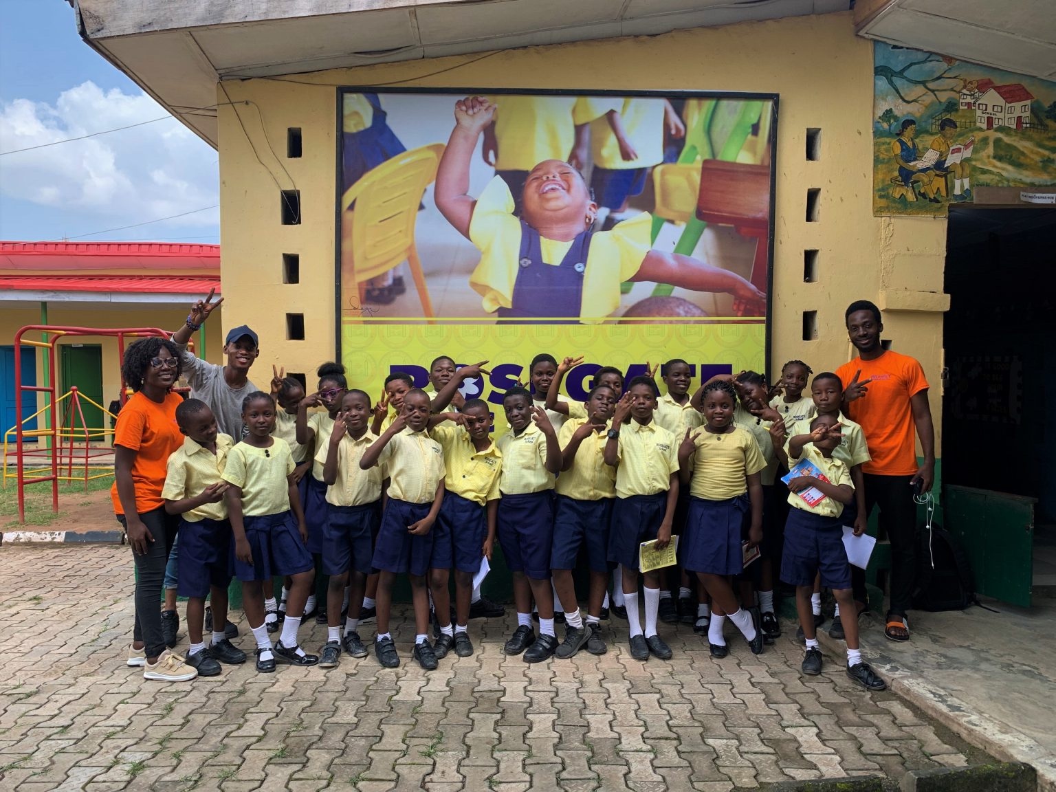 Pupils in yellow shirts with OpenKids Africa volunteers outside Rosegate Nursery and Primary School